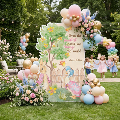 May include: A decorative sign featuring Peter Rabbit and a duck, with a tree and fence illustration. The sign is decorated with balloons and flowers. Text on the sign reads, "Even the smallest one can change the world" -Peter Rabbit.